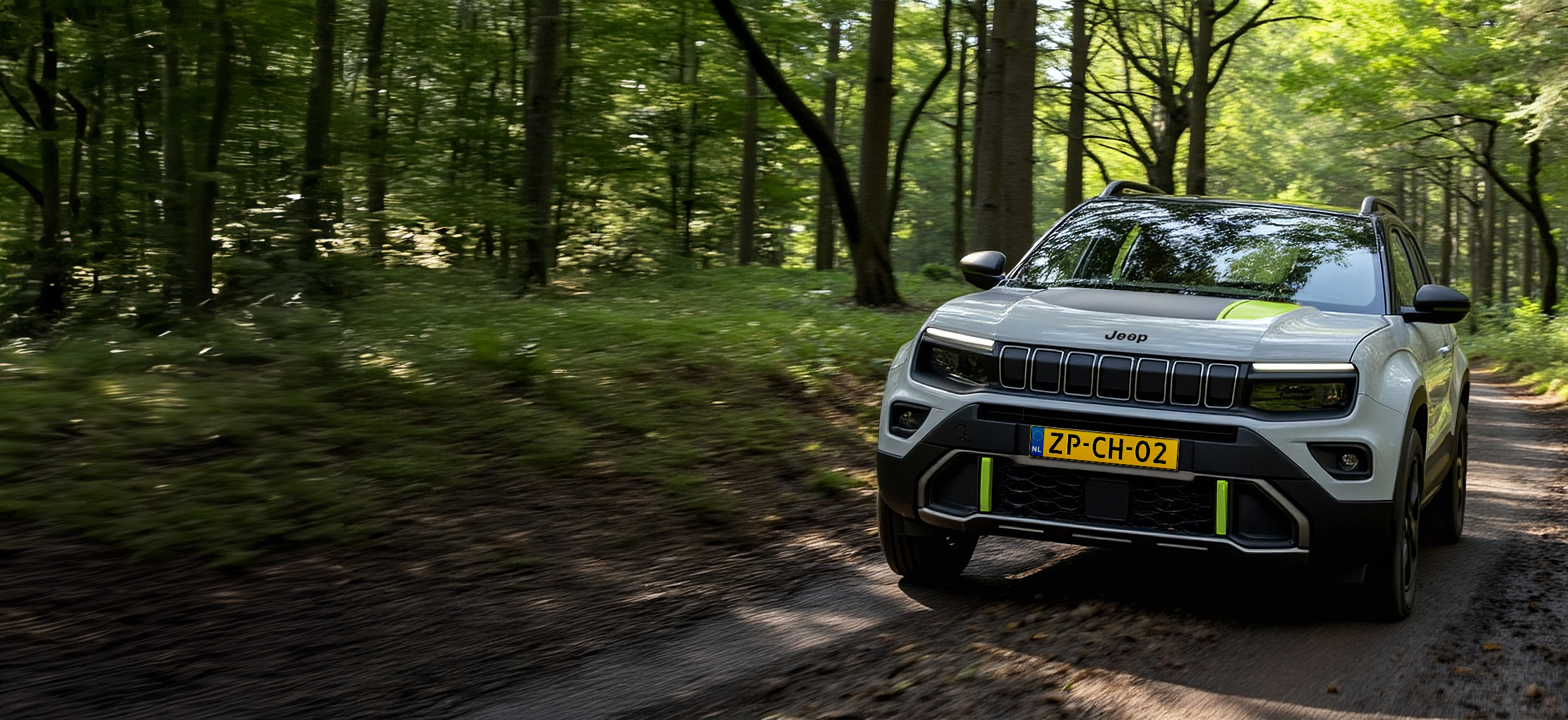 Een grijze Jeep Avenger 4XE rijdt door het bos.