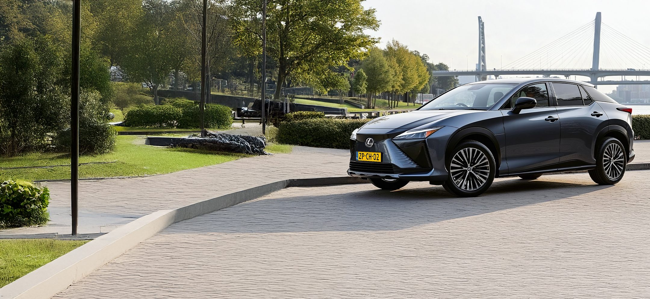 Een Lexus RZ geparkeerd aan het opladen aan een laadpaal in het park.