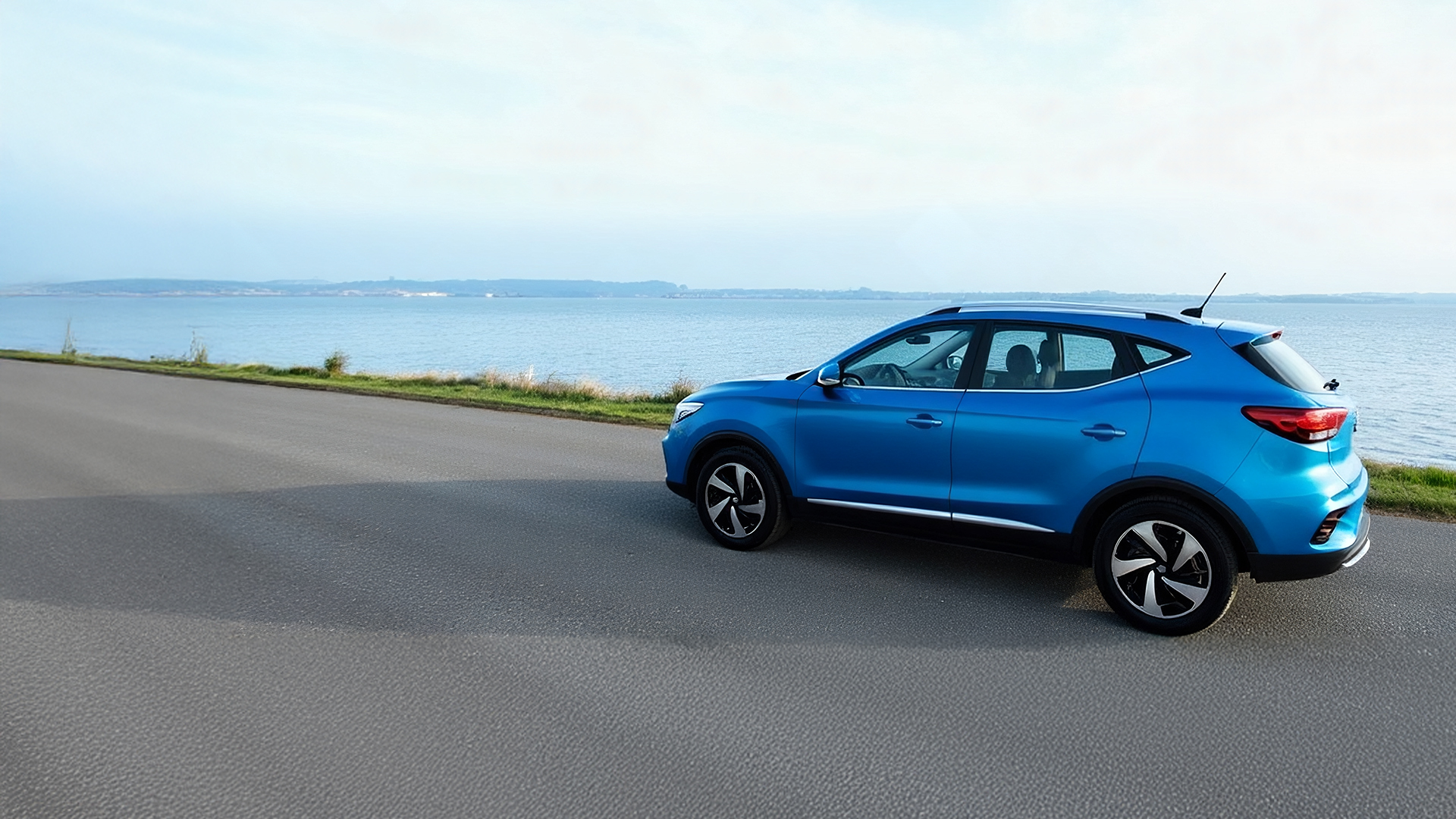 Een MG ZS EV geparkeerd langs het water.