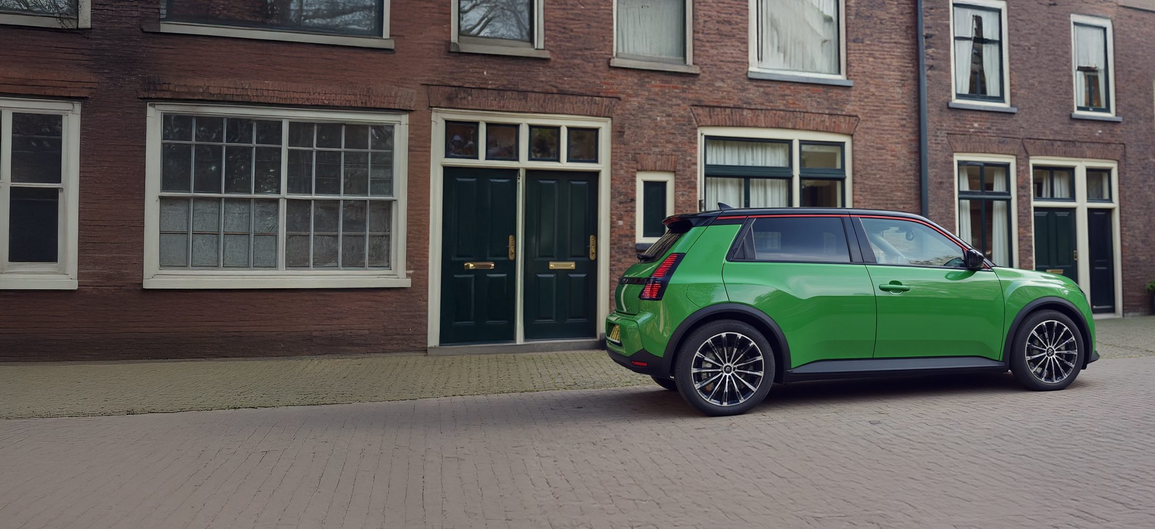 Renault 5 E-Tech geparkeerd in een Hollandse straat voor een huis met een laadpaal.