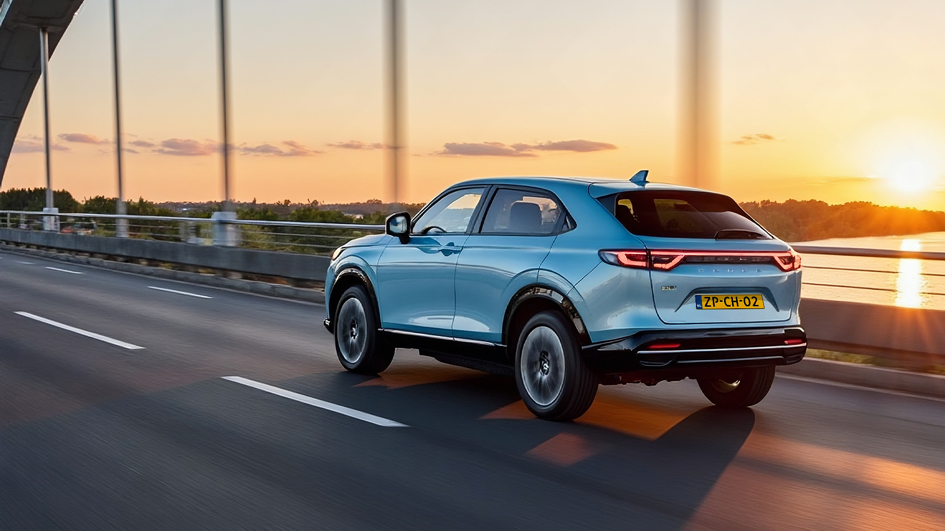 Blauwe Honda eNy1 rijdend over een brug onderweg naar huis om zijn auto op te laden aan zijn laadpaal.